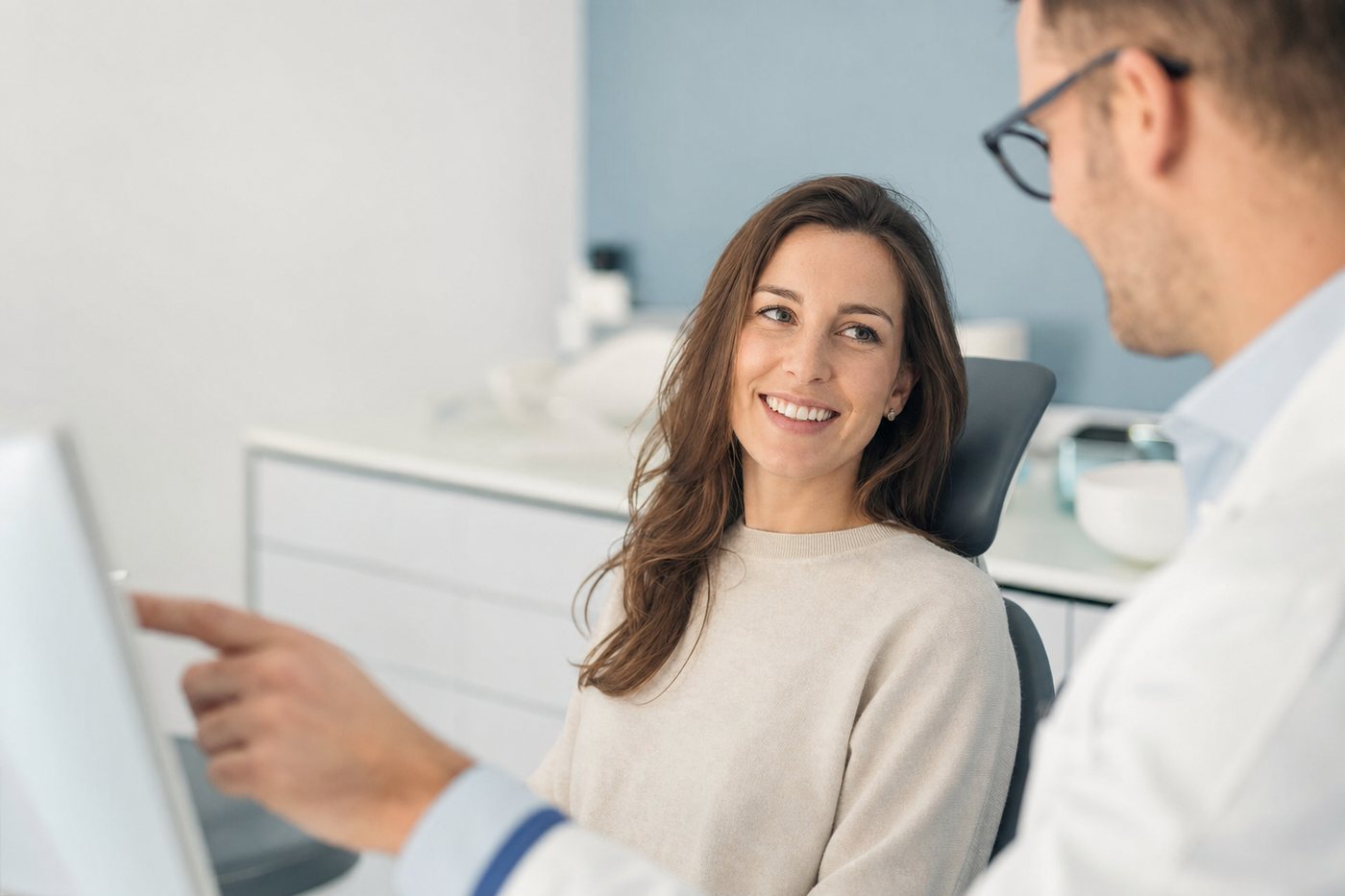 A patient smiling while a dentist reviews her treatment in a modern clinic