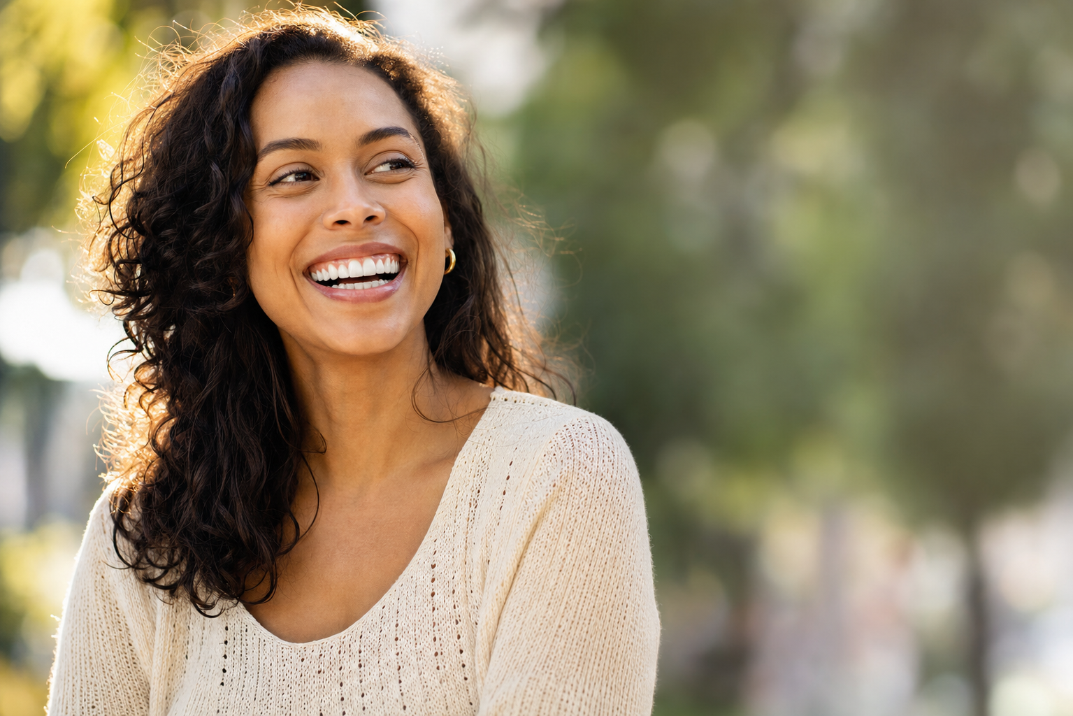 Young woman laughing with a bright, confident, straight smile in warm outdoor light